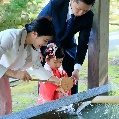 画像:手水舎で手水をおこなう家族